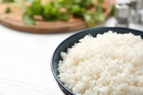 Bowl of boiled rice on table, closeup. Space for text