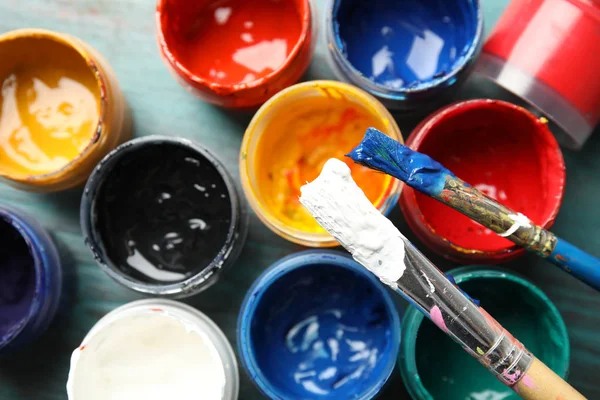 Jars with color paints and brushes on table, top view