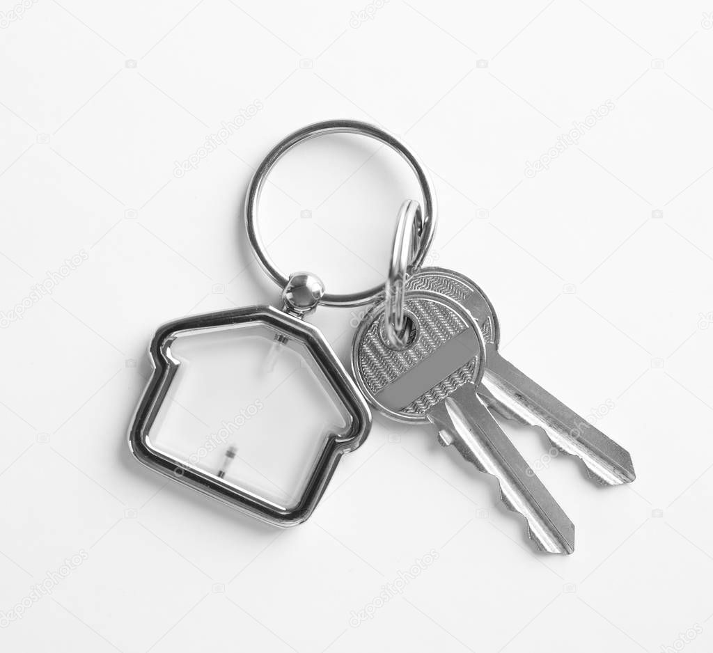 House keys with trinket on white background, top view
