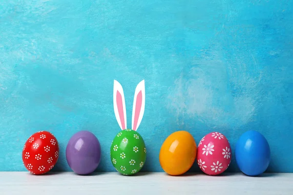 Huevos Pascua Decorados Orejas Conejito Lindo Mesa Contra Fondo Color — Foto de Stock