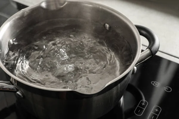 Pot with boiling water on electric stove in kitchen, closeup
