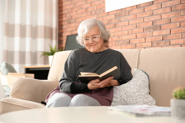 Elderly woman using smartphone on sofa in living room