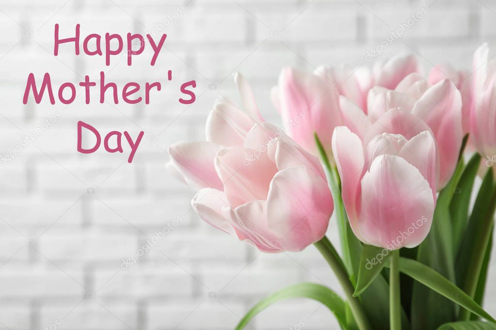 Beautiful tulips and text Happy Mother's Day against brick background, closeup