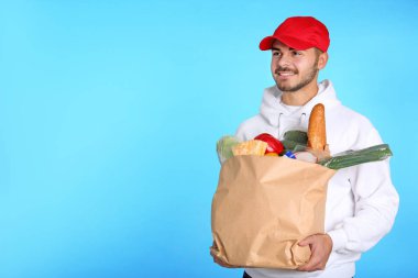 Kağıt torba renk arka plan üzerinde ürünlerle holding gıda teslim kurye. Metin için yer