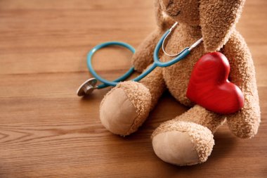 Oyuncak tavşan, stetoskop ve kalp üzerinde ahşap arka plan, portre. Çocuk doktoru