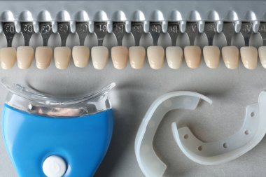 Diş beyazlatıcı, ağız kapaklar ve gölge kılavuz üstünde gri arka plan, üstten görünüm