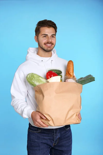 Ung Man Håller Papperspåse Med Produkter Färgbakgrund Mat Leveransservice — Stockfoto