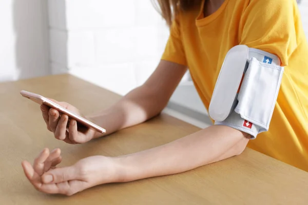 Frau Checkt Blutdruck Mit Modernem Monitor Und Smartphone Tisch Drinnen — Stockfoto