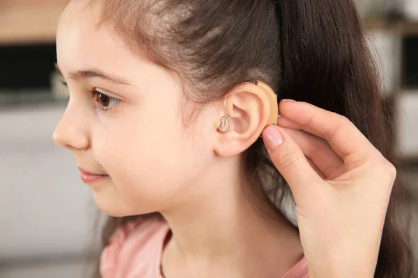 年轻女子在室内将助听器放在女儿的耳朵里 特写镜头 — 图库照片
