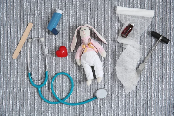 Flat lay composition with toy bunny and medical items on fabric. Children\'s doctor