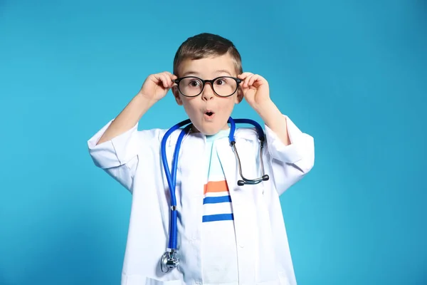 可爱的孩子在医生外套与听诊器在颜色背景 — 图库照片