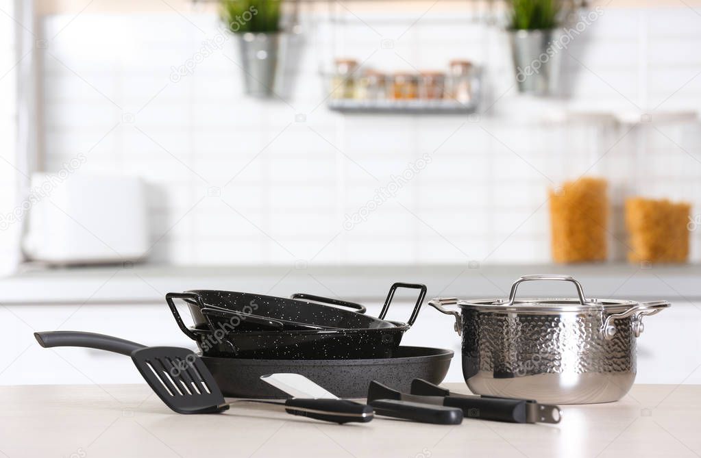 Set of clean cookware and utensils on table in modern kitchen