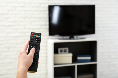 Kadın el oturma odasında, odak uzaktan kumanda ile TV kanalı değiştirme. Metin için yer