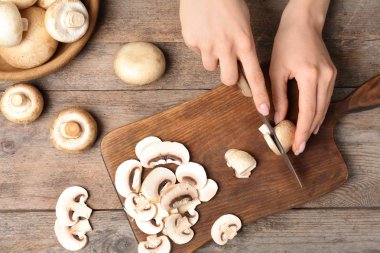 Genç kadın kesme taze champignon ahşap masa, üstten görünüm mantar