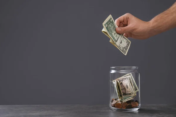 Man Putting Money Donation Jar Table Grey Background Closeup Space — Stock Photo, Image