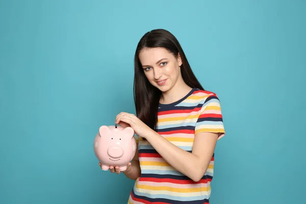 Mujer Joven Poniendo Moneda Alcancía Fondo Color — Foto de Stock