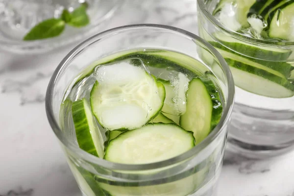 Glass with fresh cucumber water on table, closeup