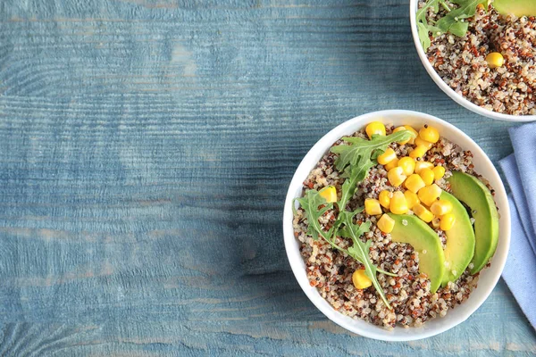 stock image Healthy quinoa salad with vegetables in bowls on wooden table, top view. Space for text