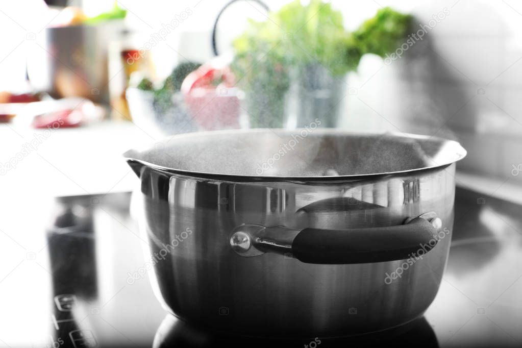 Pot with boiling water on electric stove in kitchen