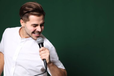 Rahat kıyafetler renk arka plan üzerinde mikrofon ile şarkı genç yakışıklı adam. Metin için yer