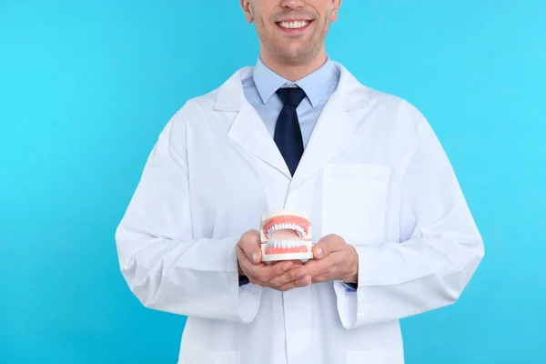 男性の歯科医が顎モデル色の背景上に保持しています — ストック写真