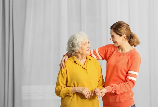 Mujer Anciana Con Cuidadora Femenina Sobre Fondo Borroso —  Fotos de Stock