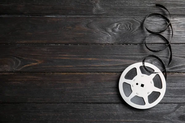 Movie reel on wooden background, top view with space for text. Cinema production