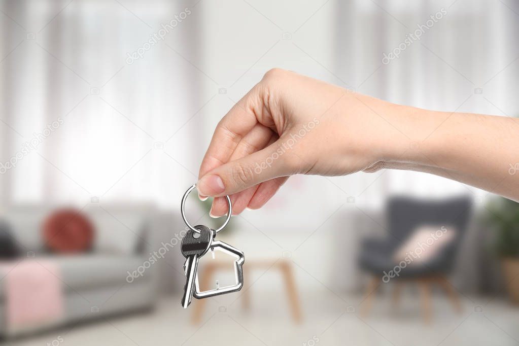 Woman holding house key in modern living room, closeup