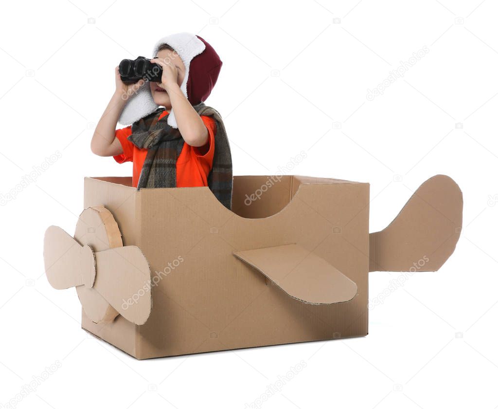 Cute little boy playing with binoculars and cardboard airplane on white background