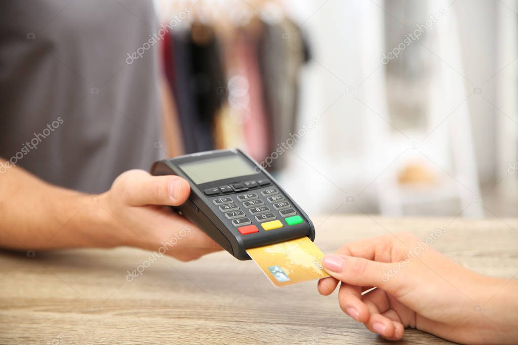 Woman using terminal for credit card payment in shop, closeup