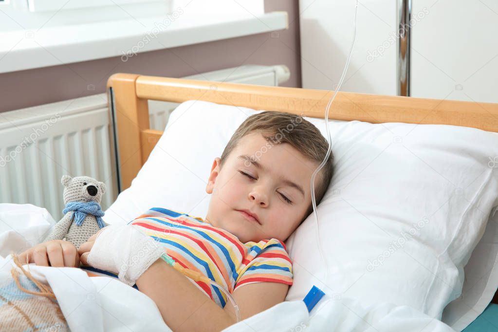 Little child with intravenous drip sleeping in hospital bed