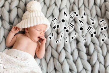 Şirin Bebek yatak ve uçan müzik notlar, üstten görünüm üzerinde uyku örgü şapkalı. Ninni şarkı