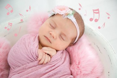 Şirin yeni doğmuş kız bebek yuvada yalan ve müzik notlar, closeup uçan. Ninni şarkı