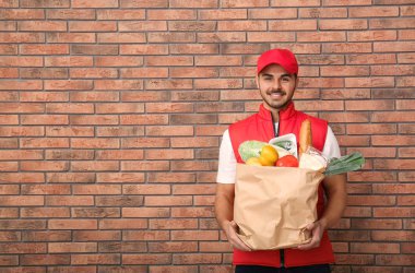 Kağıt torba tuğla duvar yanında ürünleri ile holding gıda teslim kurye. Metin için yer
