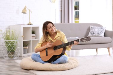 Genç kadın oturma odasında akustik gitar çalmak