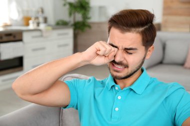 Genç adam sürtünme göz evde. Kaşıntı rahatsız edici