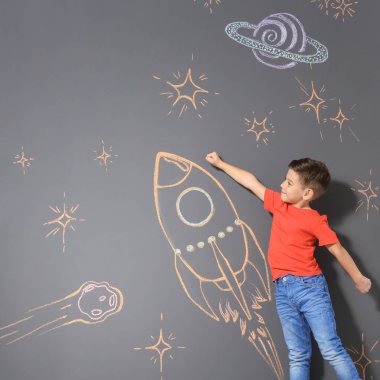 Tebeşir roket gri arka plan üzerinde çizim ile oynayan sevimli küçük çocuk