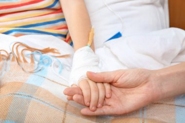 Doktor hastanede, closeup intravenöz damla ile küçük çocuğun elini tutarak