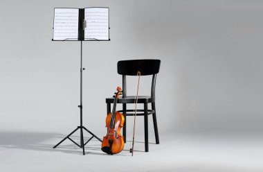 Keman, sandalye ve Not müzik sayfaları gri arka plan üzerinde stand. Metin için yer
