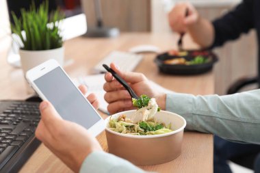 Ofis çalışanı ile smartphone işyerinde, closeup öğle yemeği. Food teslim