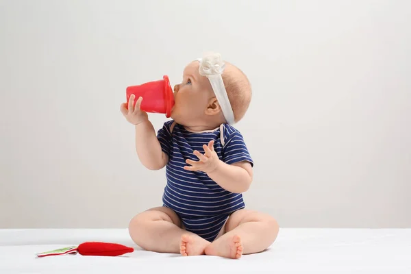 シッピー カップとグッズ飴と明るい背景を持つ少女 赤ちゃんのアクセサリー — ストック写真