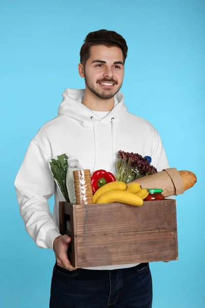 Giovane Uomo Che Tiene Cassa Legno Con Prodotti Sfondo Colore — Foto Stock