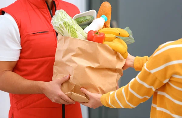 Male courier delivering food to client indoors, closeup