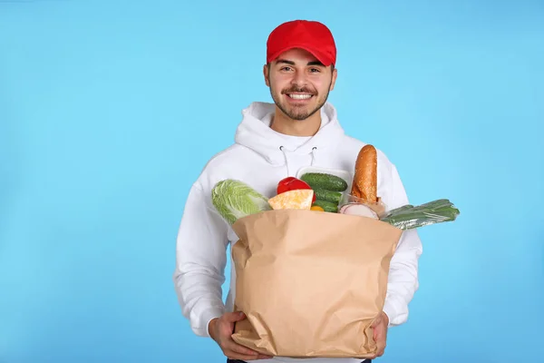 Junger Mann Mit Papiertüte Mit Produkten Auf Farbigem Hintergrund Essenslieferdienst — Stockfoto