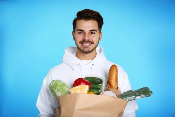 Junger Mann Mit Papiertüte Mit Produkten Auf Farbigem Hintergrund Essenslieferdienst — Stockfoto