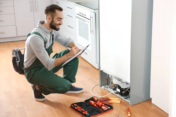 Mannelijke Technicus Met Klembord Onderzoeken Koelkast Keuken — Stockfoto