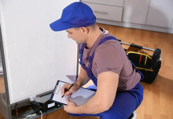 Mannelijke Technicus Met Klembord Onderzoeken Koelkast Keuken — Stockfoto