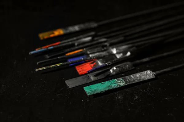 Tattoo needles covered with colorful inks on black background, closeup