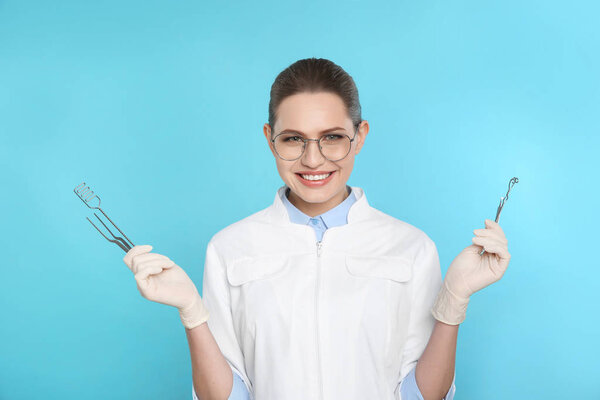 Female dentist holding professional tools on color background