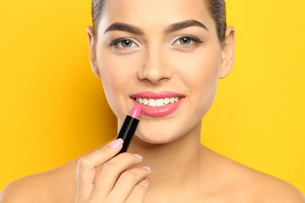 Mujer Joven Aplicando Lápiz Labial Sobre Fondo Color — Foto de Stock